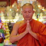 stock-footage-closeup-of-a-buddhist-monk-with-orange-robe-pray-in-temple